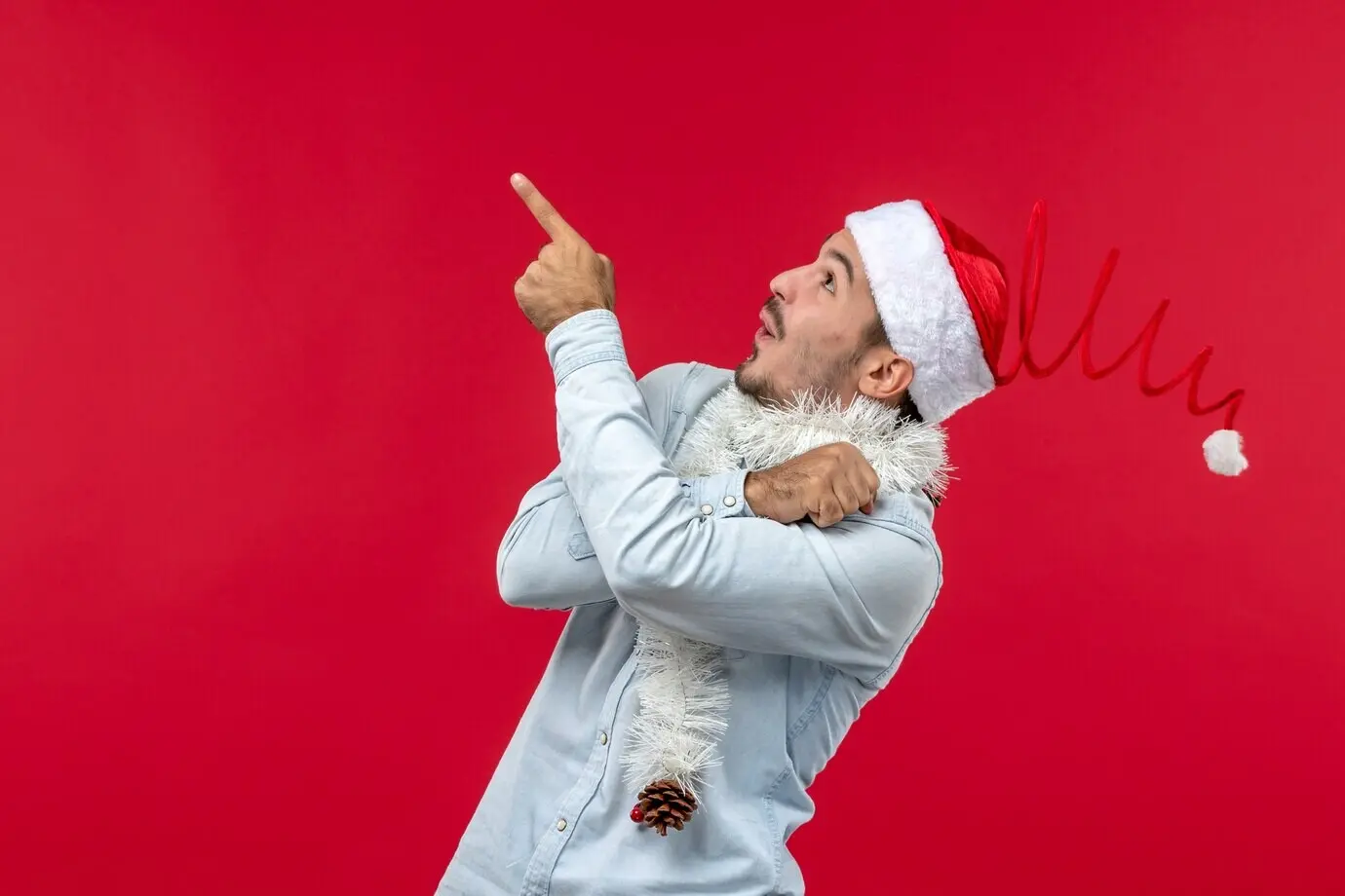 Front view of a young man looking at the ceiling against a red wall